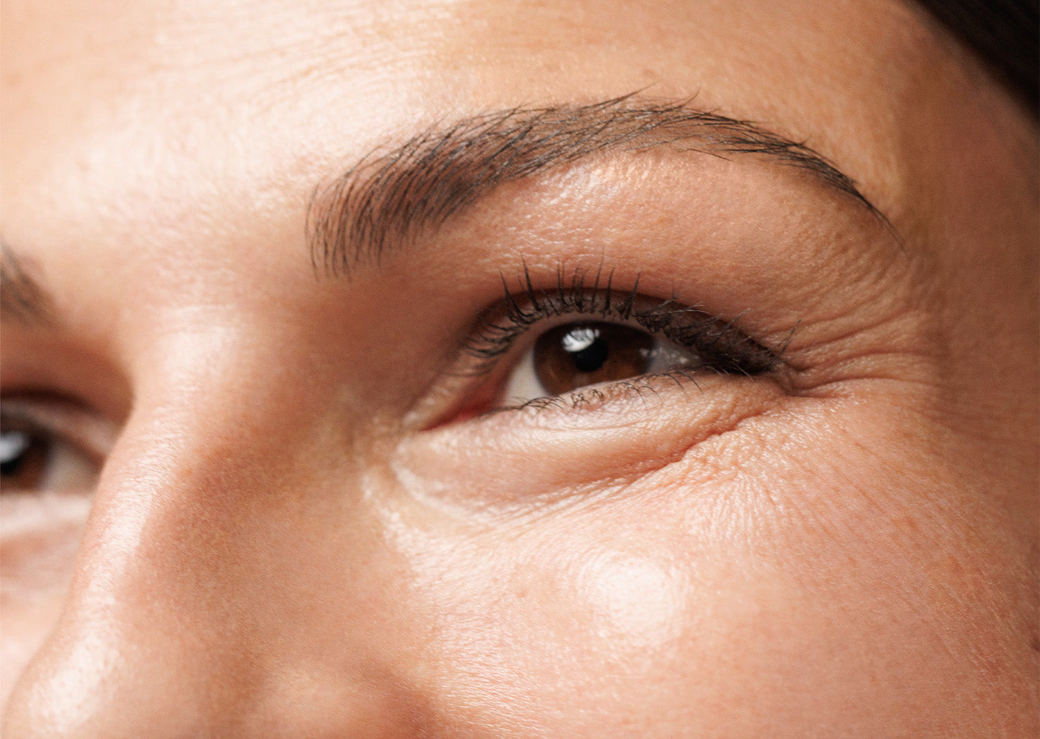Close-up of an eye with fine lines, on the topic of skincare targeting anti-aging, discoloration, and redness concerns.