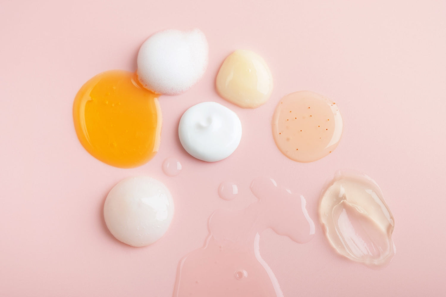 Various skincare textures displayed on a pink surface, visually representing AM and PM layering routines