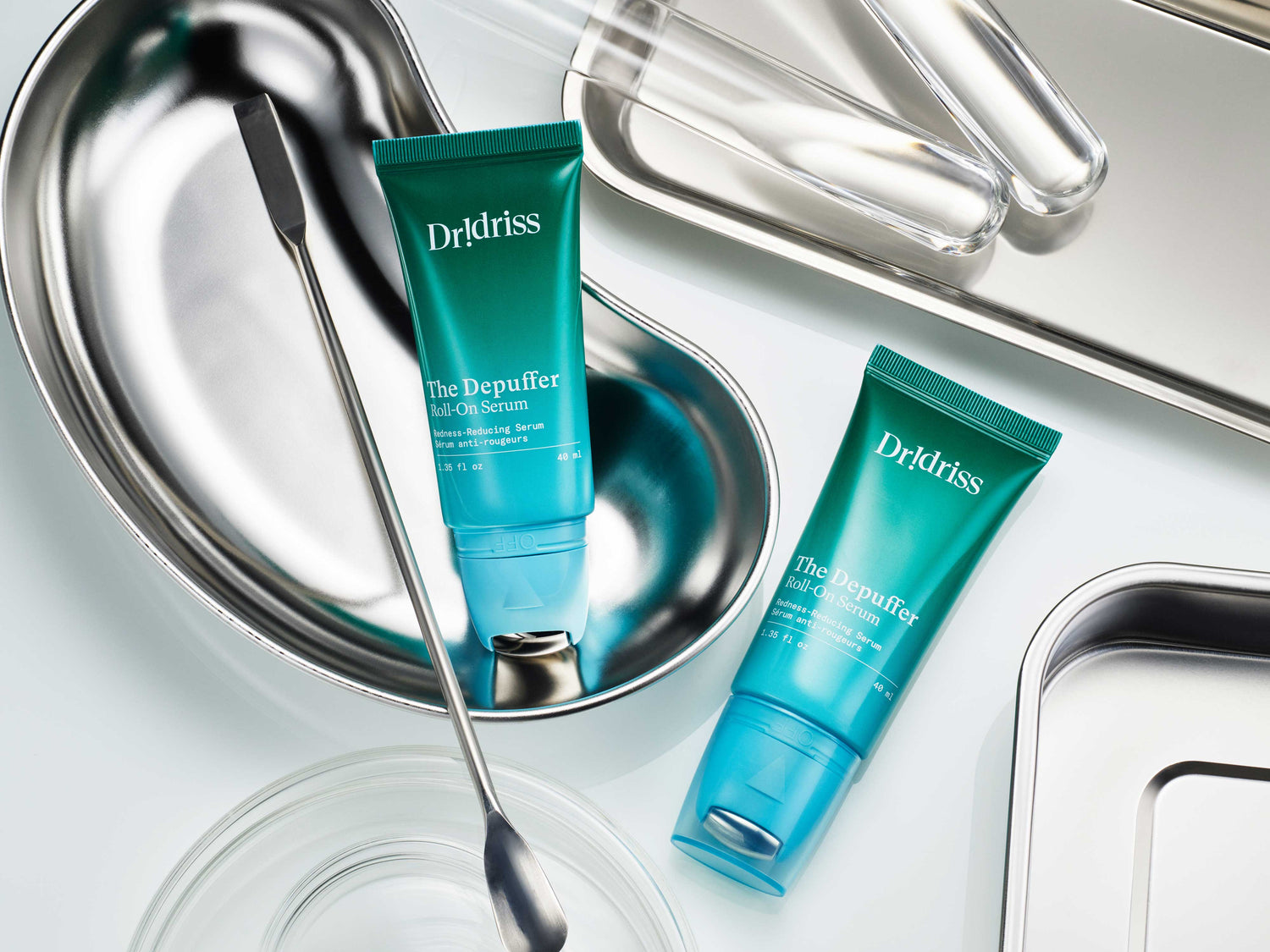 Two Dr. Idriss Depuffer Roll-On Serums with on chrome backgrounds, highlighting its anti-puffiness skincare benefits and cooling applicator