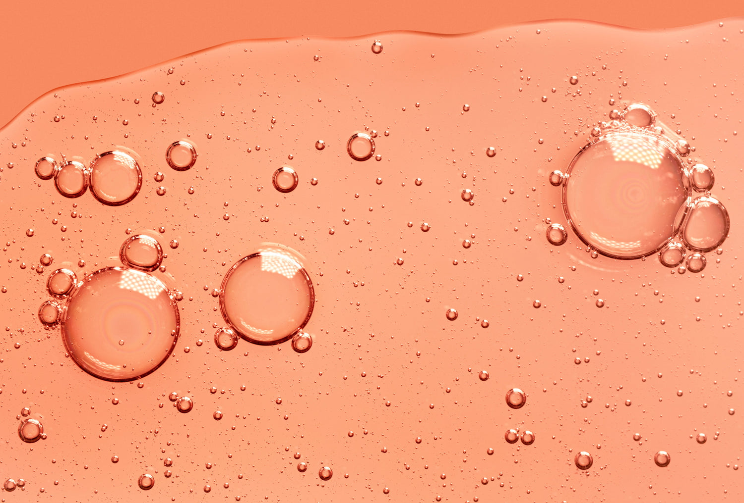 A pink-orange gel texture representing vitamin C skincare formulations and the science behind them