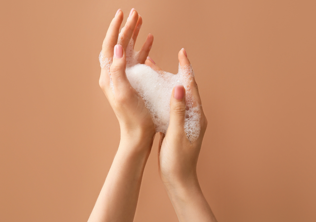 Close-up of hands creating a lather with foamy soap, featuring an article covering 6 key body skincare ingredients