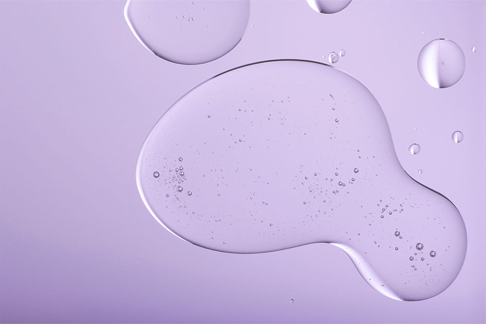 Drops of glycolic acid against a purple background