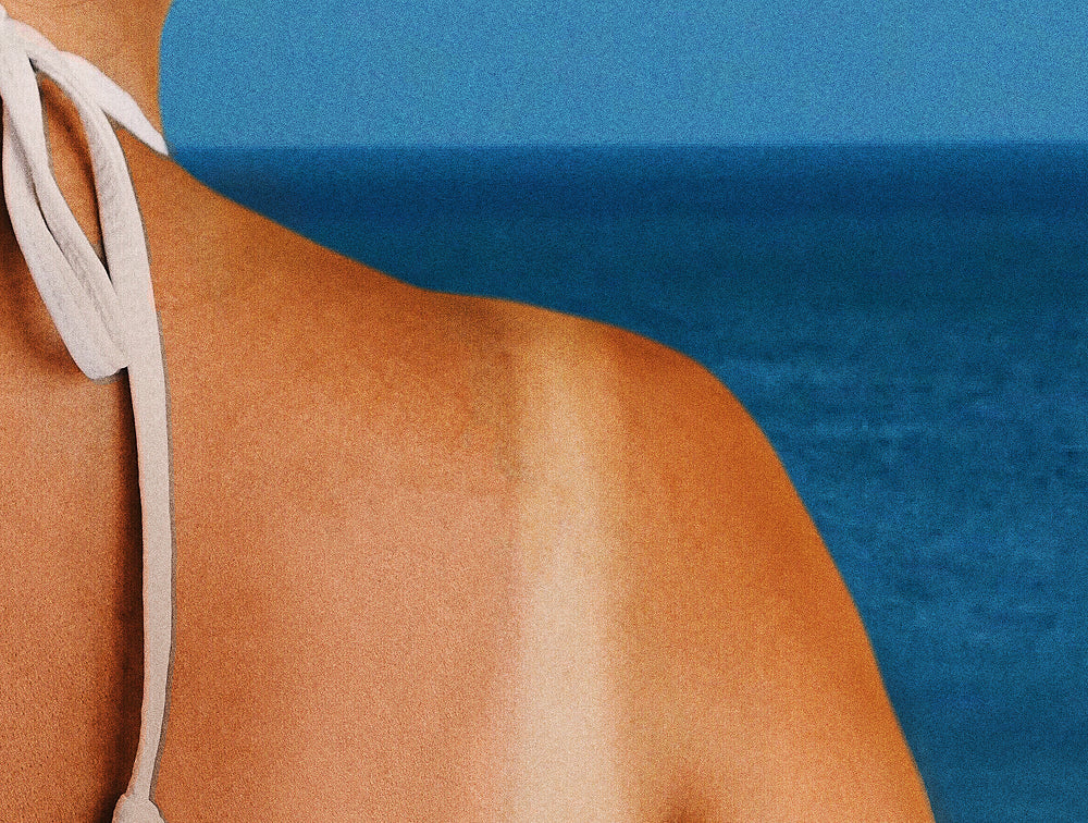 Model on a beach showing a tan line on her shoulder