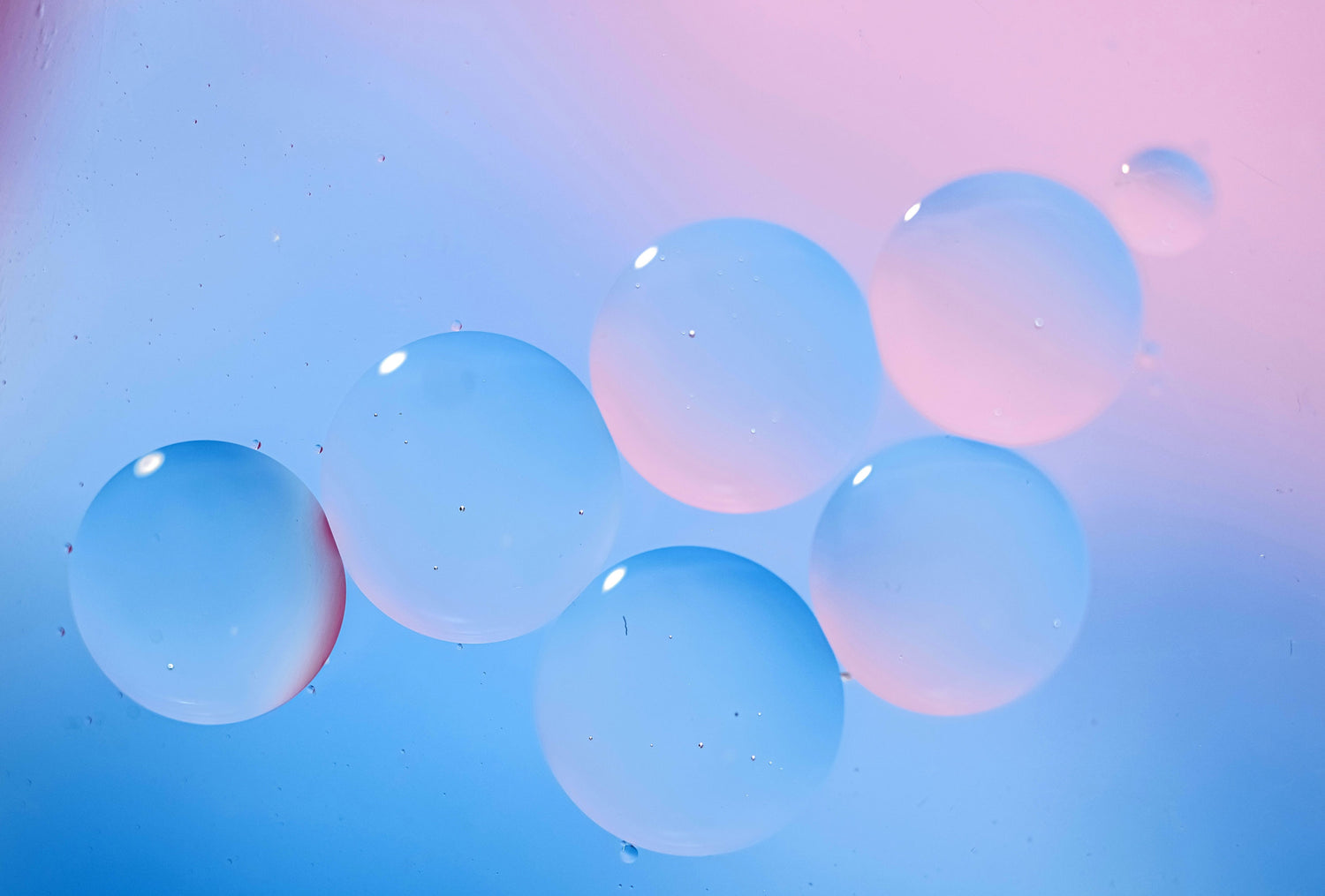Bubbles on a blue-pink gradient background, representing hyaluronic molecules for an article about hyaluronic acid