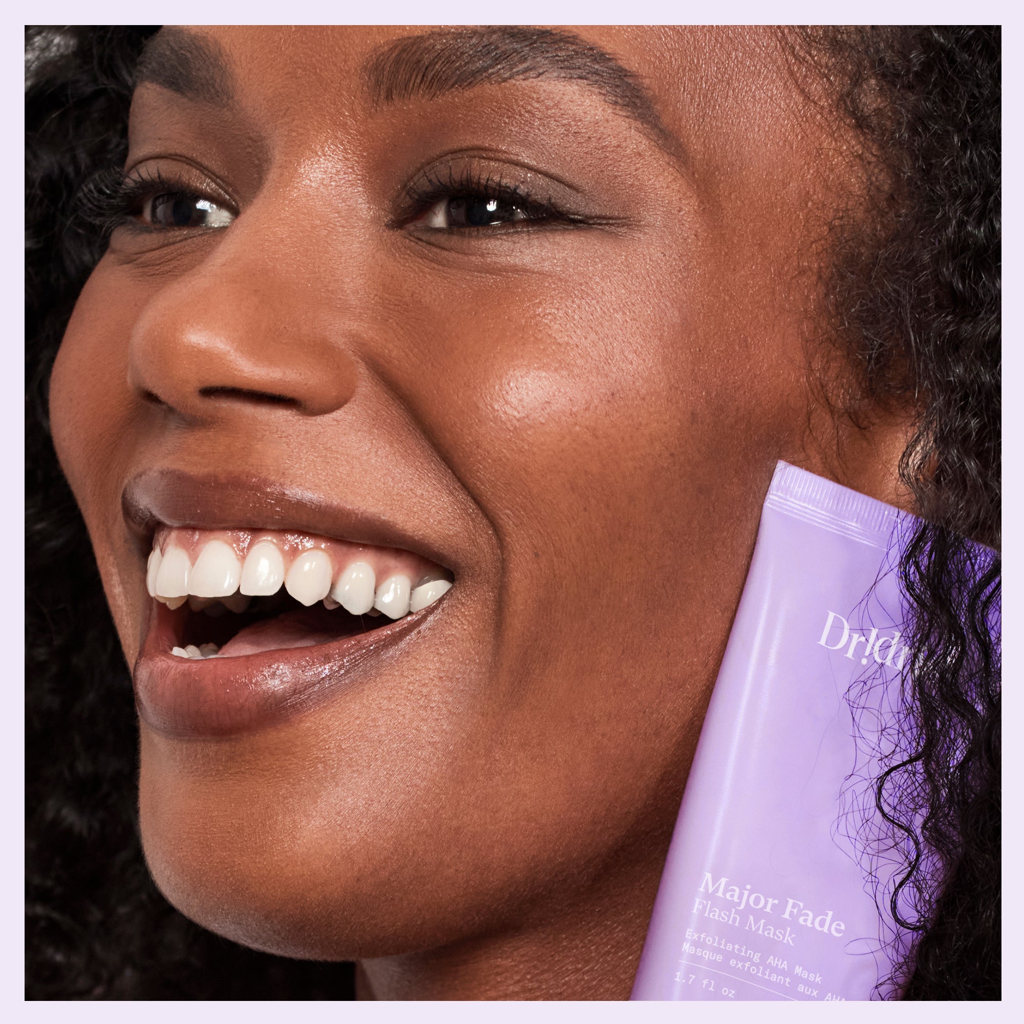 Glowing model holding Major Fade Mask, powered by AHAs for exfoliation and radiance